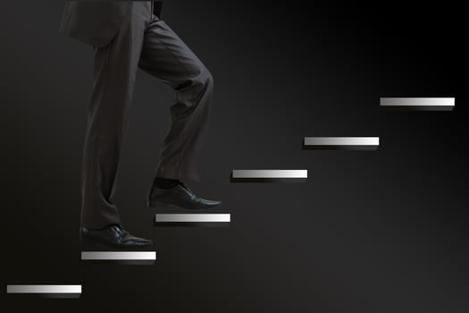 Businessman climbing the career stairs drawn on a chalkboard with copy space photo