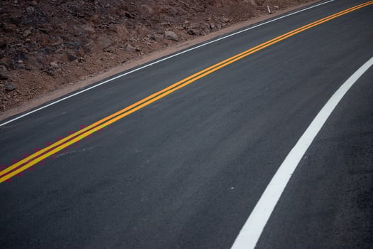 The asphalt road has yellow and white traffic lines crossing the mountains. photo
