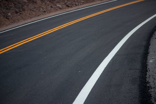 The asphalt road has yellow and white traffic lines crossing the mountains. photo