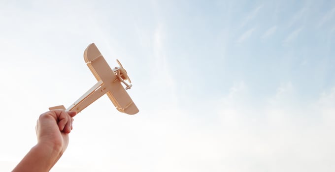 Freedom concept, human hand holding wooden plane on the sunset sky background photo