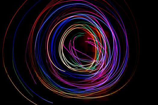 Multi color light painting photography, swirl and curve of blue, green and red light against a black background. photo