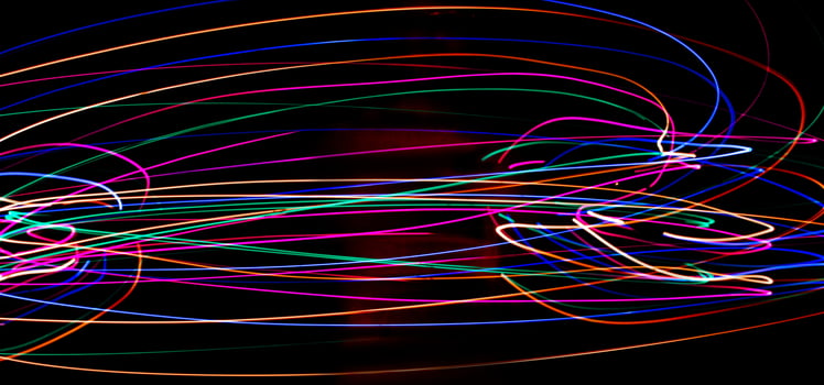 Multi color light painting photography, swirl and curve of blue, green and red light against a black background. photo