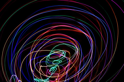 Multi color light painting photography, swirl and curve of blue, green and red light against a black background. photo