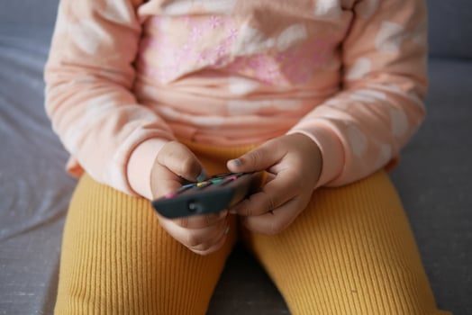 close up of child hand holding tv remote sitting on sofa photo