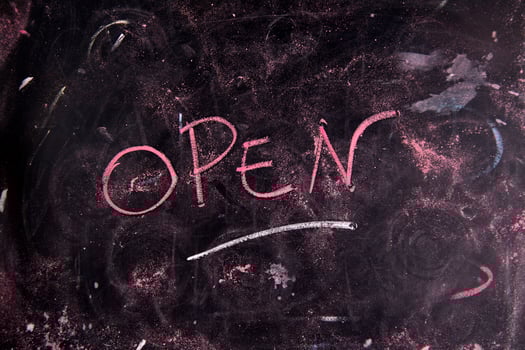 open written on a blackboard with a pink marker photo