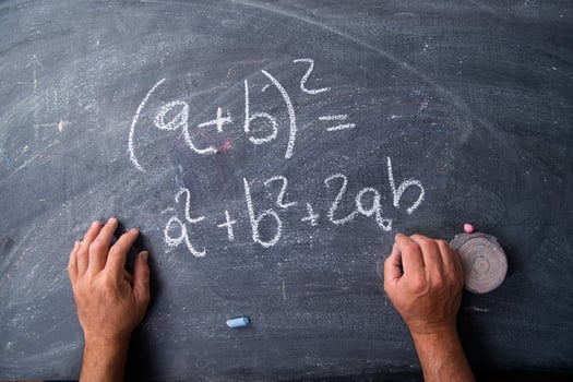 hands writing on a blackboard with math equations photo