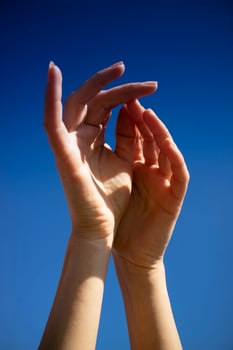 Female hands in the blue sky in the backlight photo
