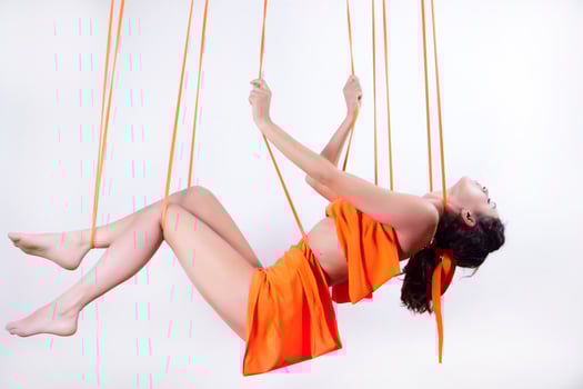 Girl in orange dress hanging on ropes photo