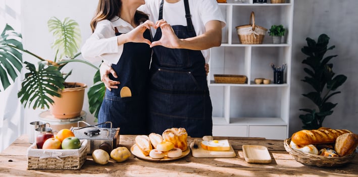 Young happy couple is enjoying and preparing healthy meal in their kitchen and reading recipes on the laptop. photo