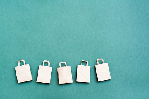 Eco-friendly craft paper shopping bags in a row on a green background. Black friday gift sales. Copy space photo