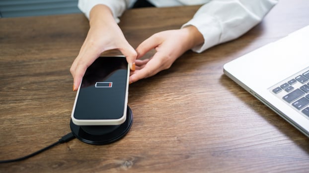 Charging mobile phone battery with wireless charging device in the table. Smartphone charging on a charging pad. Mobile phone near wireless charger Modern lifestyle technology concept. photo