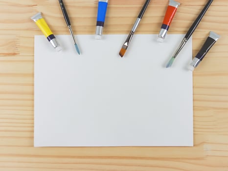 flat lay of artist workspace. Blank paper, Drawing tools, stationary supplies, Watercolor paints and brushes and paper on wooden table, copy space. photo