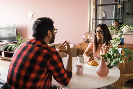 Happy indian couple having breakfast and small talk together in the kitchen - friendship, dating and family photo