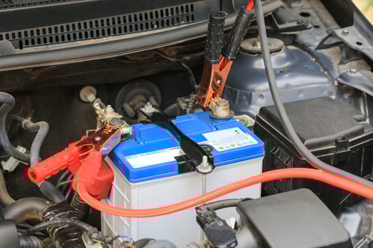 Car mechanic uses battery jumper cables charge a dead battery. photo