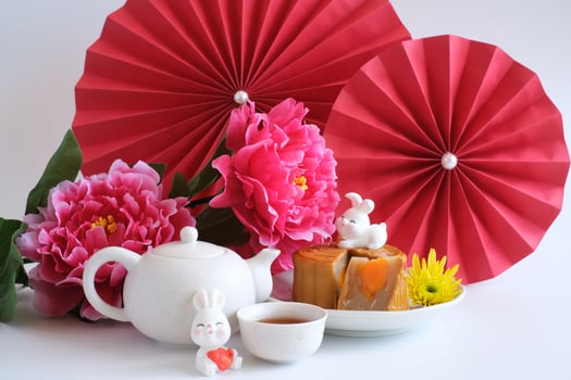 Chinese Mid-Autumn Festival concept made from mooncakes, tea decorated with plum blossom, red paper fans and rabbits isolated on white background. photo