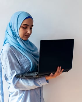 Young Arabian Muslim woman in hijab holding laptop pc computer photo