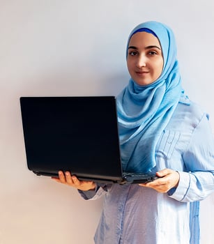 Young Arabian Muslim woman in hijab holding laptop pc computer photo