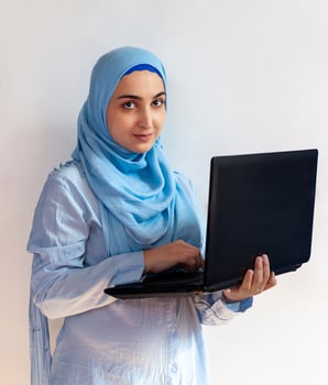 Young Arabian Muslim woman in hijab holding laptop pc computer photo