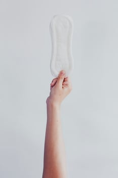 Woman hanging up sanitary pad against white background. Period days concept showing feminine menstrual cycle. photo