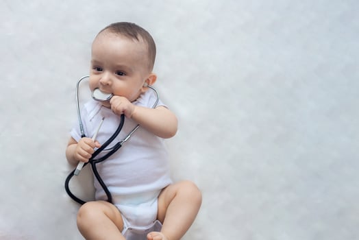 Little cute baby doctor. 6-month old baby boy playing with stethoscope. Kid having fun like a doctor photo