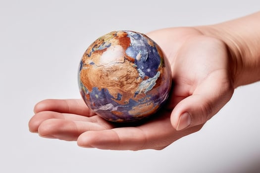 Miniature Earth in Hand - Close-up of Intricate Planet Surface on White Background - photo