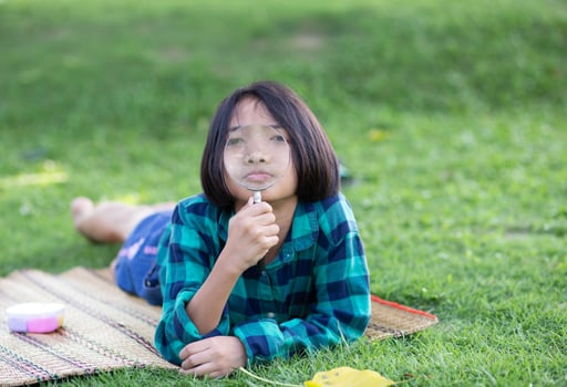 Asian little girl is using magnifying glass to play in the park.SSTKHome photo
