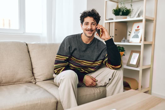 Confident man freelance smile phone sitting lifestyle couch internet cell talking success home photo