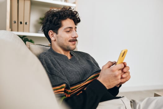 Freelance man technology message room communication lifestyle internet sofa phone wireless home typing photo