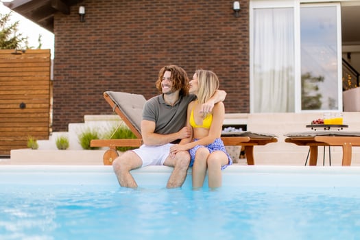 Young couple relaxing by the swimming pool in the house backyard photo