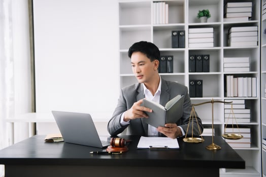 Asian man lawyer reading legal book with gavel on table in office. justice and law ,attorney concept. photo
