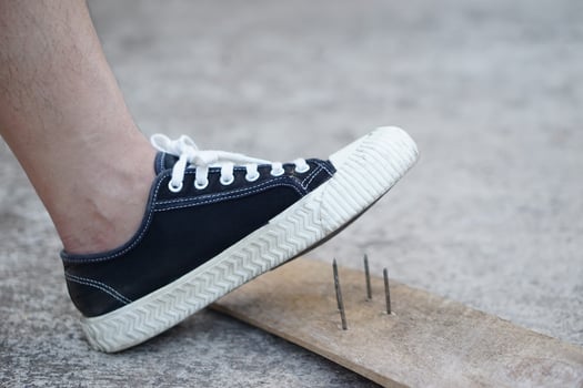 Closeup man wear shoes is stepping on rusty metal nail on wood. Concept, unsafe , risk for dangerous tetanus. Be careful and look around during walking  on the floor or risk places. Accident photo