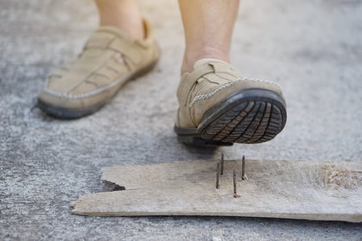 Closeup man wear shoes is stepping on rusty metal nail on wood. Concept, unsafe , risk for dangerous tetanus. Be careful and look around during walking  on the floor or risk places. Accident photo