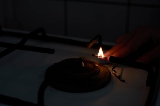 Woman trying to turn on gas with a match flame photo