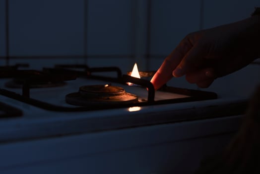 Woman trying to turn on gas with a match flame photo