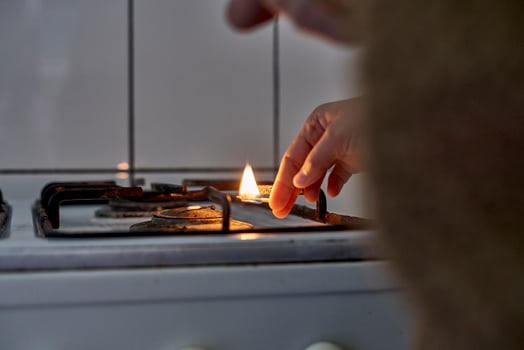 Woman trying to turn on gas with a match flame photo
