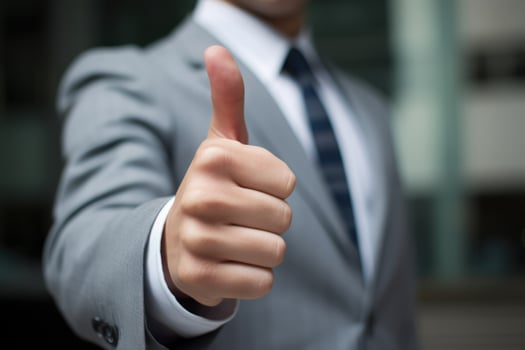 a man in a suit is enthusiastically showing his approval or agreement by giving a thumbs up sign. He appears to be in a positive and reassuring mood, possibly in a professional business setting. photo