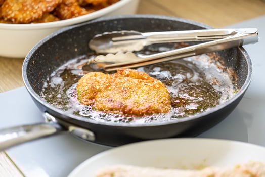 Pan full of oil is used for frying breaded meat while making wiener schnitzels photo