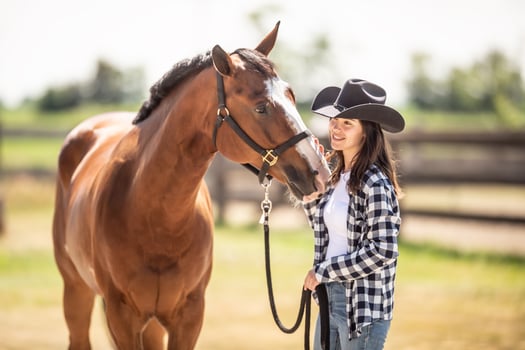 A bond between a horse and a young woman in cowboy hat on a ranch outdoors photo