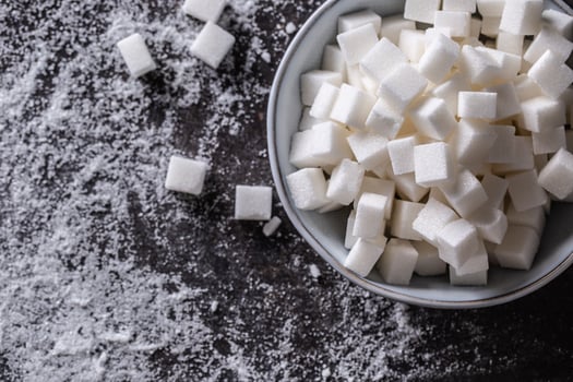 White sugar cubes in a blue bowl on the table photo