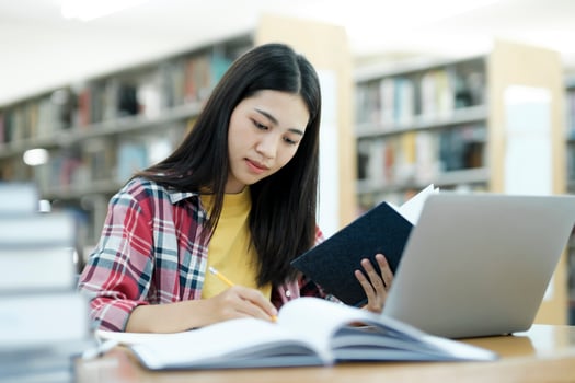 Young university student using laptop for online learning, searching and learning at library. photo