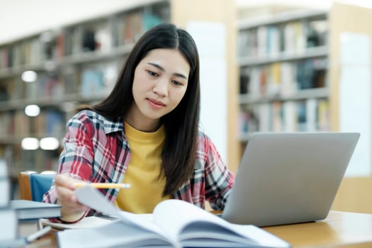 Young university student using laptop for online learning, searching and learning at library. photo
