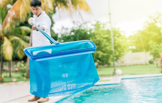 Person with skimmer cleaning pool. Man cleaning the pool with the Skimmer, A man cleaning pool with leaf skimmer. Hands holding a skimmer with blue pool in the background photo