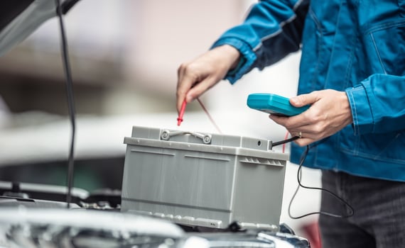 Car repaid garage technician checks lifespan of a car batery with a multimeter photo