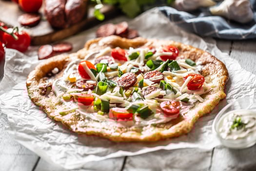 Traditional hungarian combo made of deep fried crusty langos with garlic edges, precisely served with cream, grated cheese, tomatoes and domestic sausages also with extra cream in little bowl photo