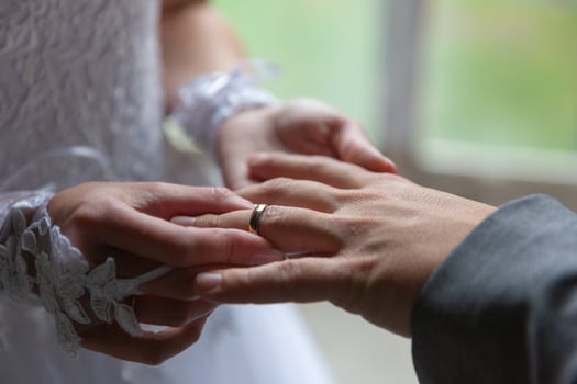 Bride putting the wedding ring on groom finger close up photo