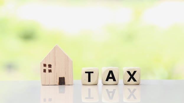 Miniature house and tax wooden cube for Investment property concepy photo