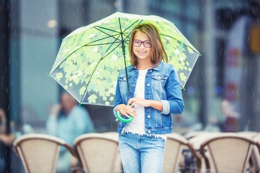 Portrait of beautiful young pre-teen girl with umbrella under ra photo