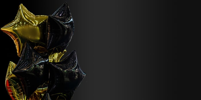 A group of black and gold balloons on a black background with copy space photo