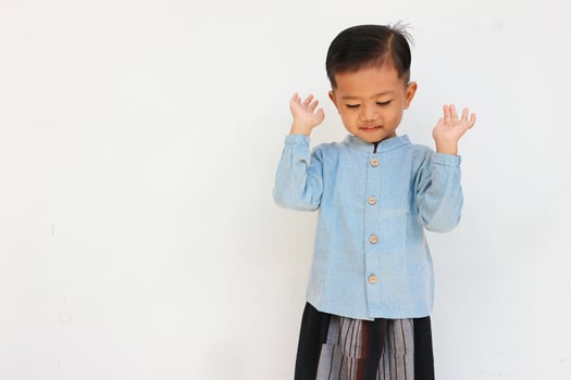 A cute handsome little boy with blue shirt and sarong praying to Allah photo
