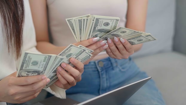 Close up hand Two asian girls counting money dollars at home. Online business success consept. photo